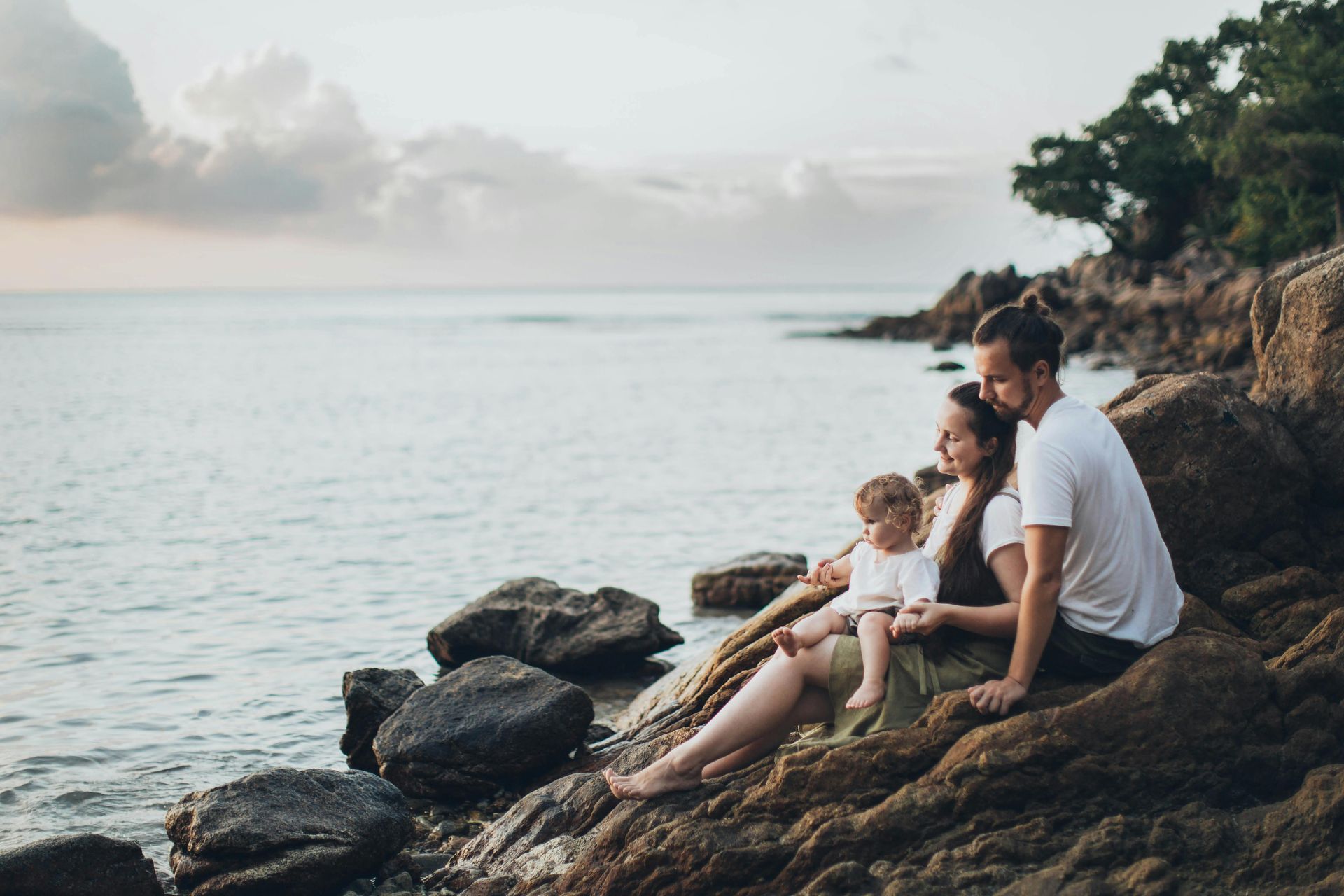 A family is sitting on rocks near the ocean.