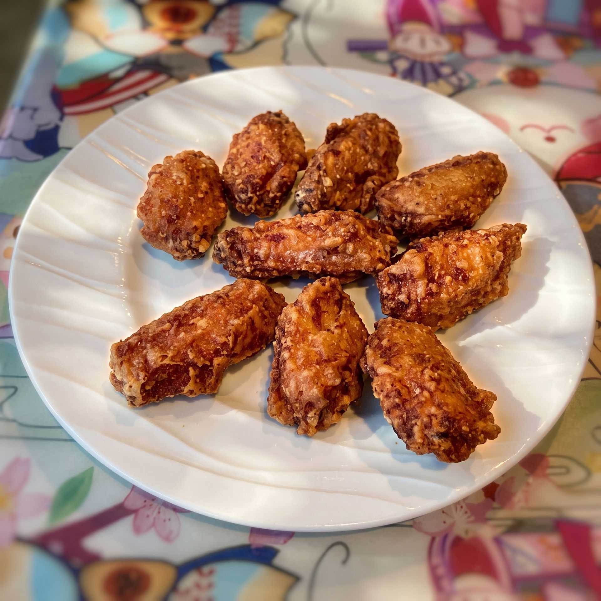 Plate of golden-brown fried snacks on a white dish on a patterned tablecloth