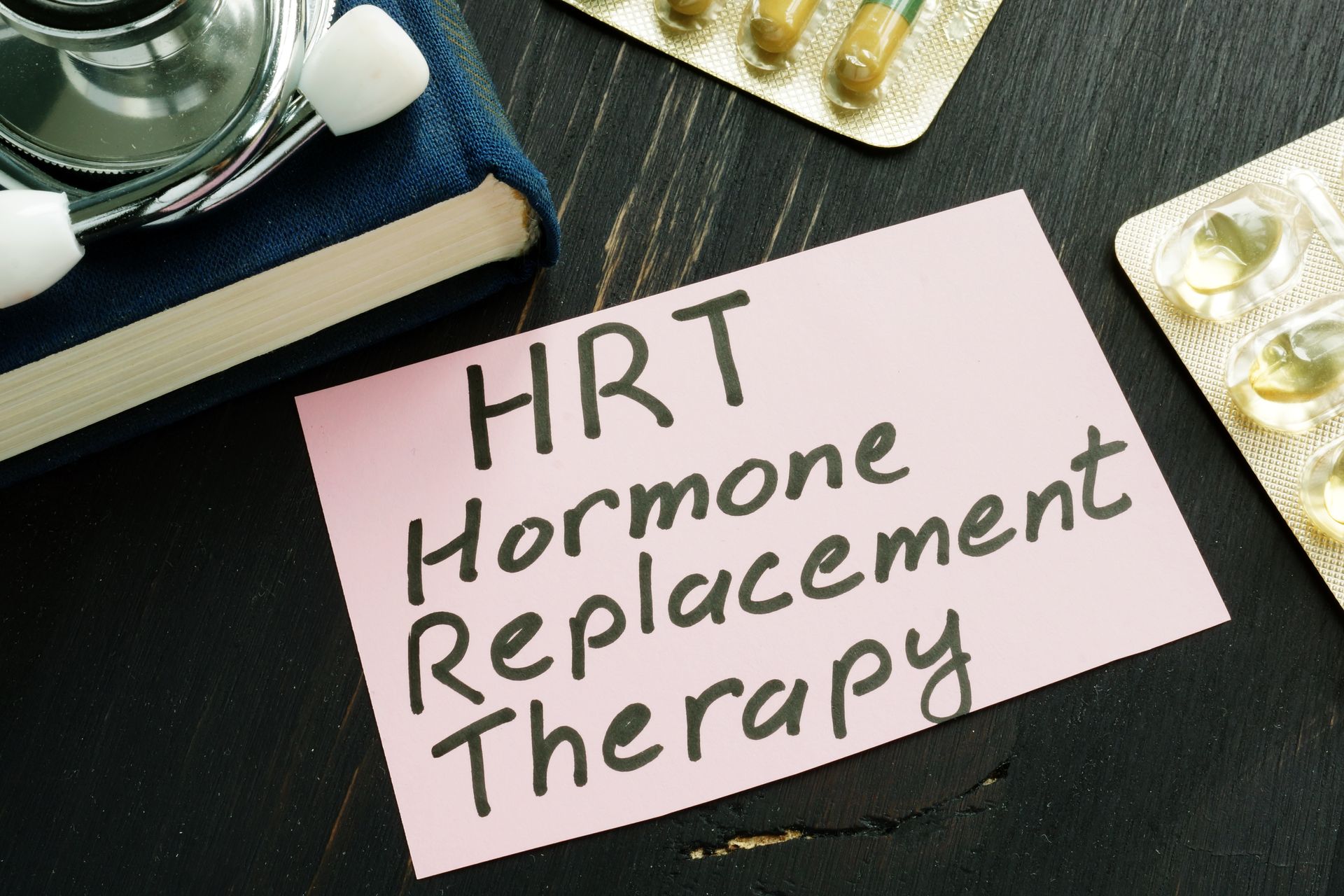 “HRT Hormone Replacement Therapy” written on a Post-it note, stethoscope and pill blisters. “HRT Hormone Replacement Therapy” written on a Post-it note, stethoscope and pill blisters.