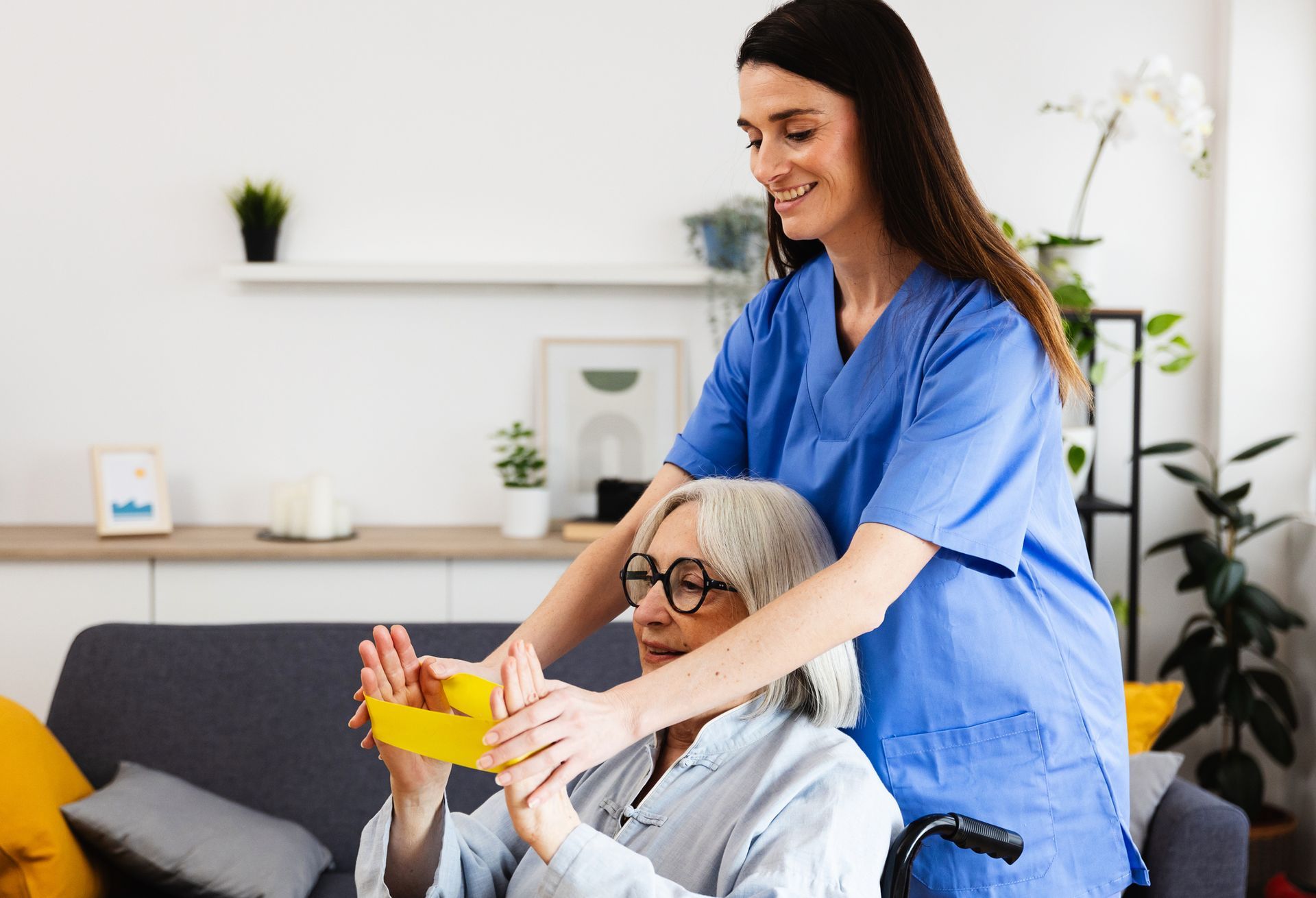 Nurse assisting elderly woman with physical therapy exercises at home.