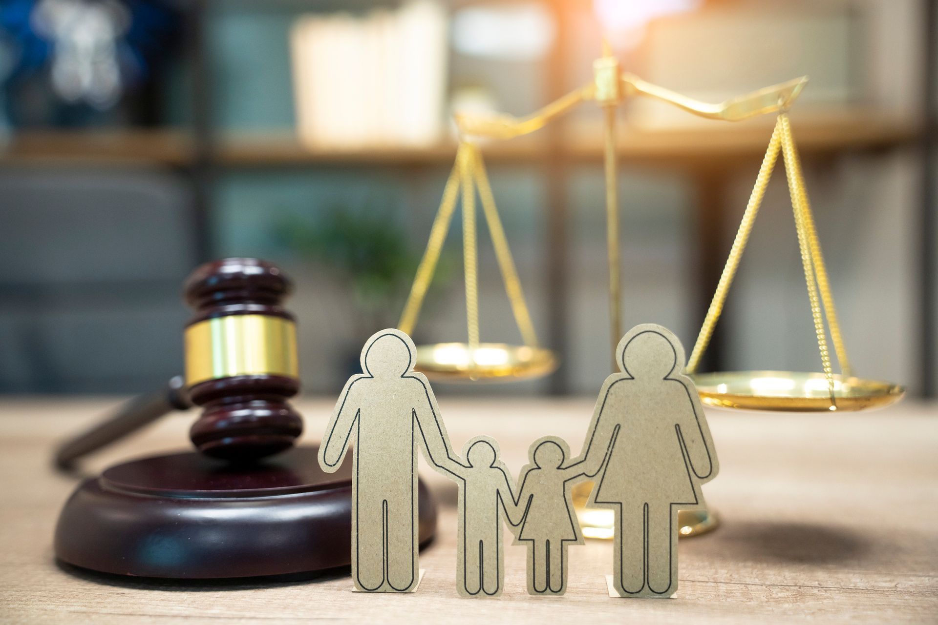A wooden family is sitting on a wooden table next to a judge 's gavel and scales of justice.
