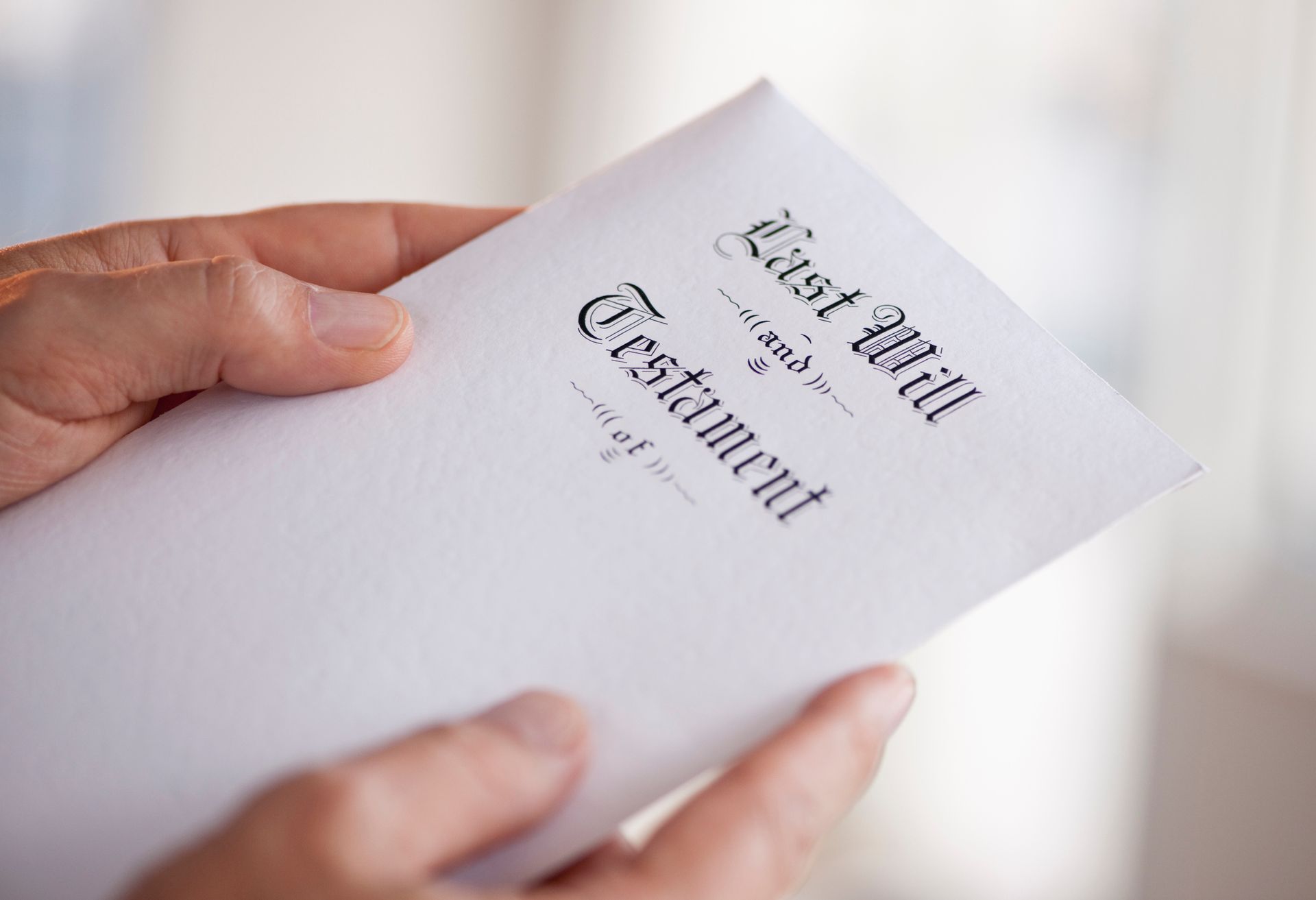 A person is holding a last will and testament in their hands