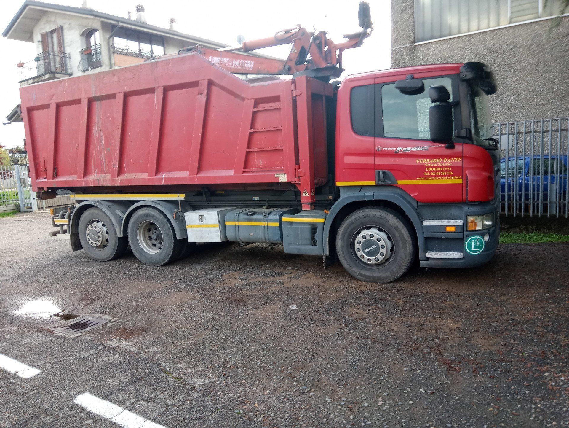 Un camion con cassone ribaltabile rosso è parcheggiato davanti a un edificio