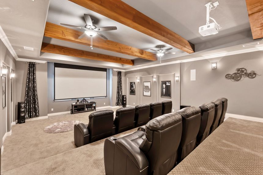 Spacious home theater with leather recliners, a large screen, and wood-beamed ceiling lights