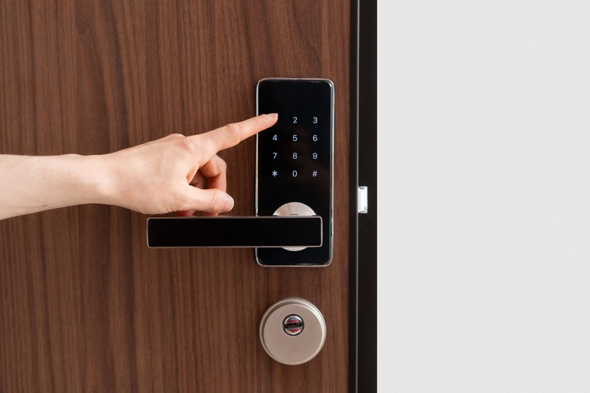Hand pressing a keypad smart lock on a wooden door