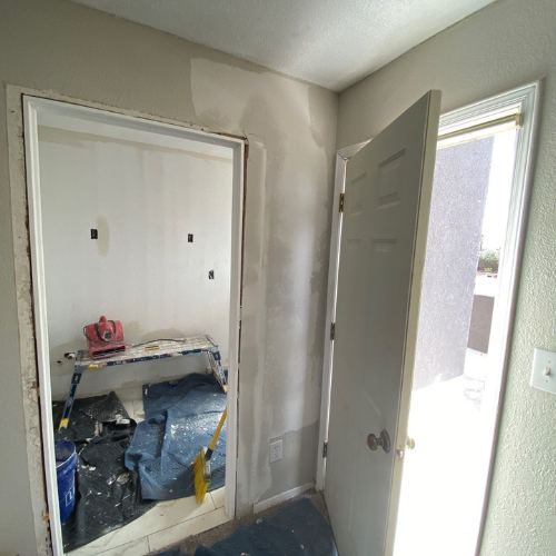 Interior view: doorway to a room under renovation, open door to an outdoor area.