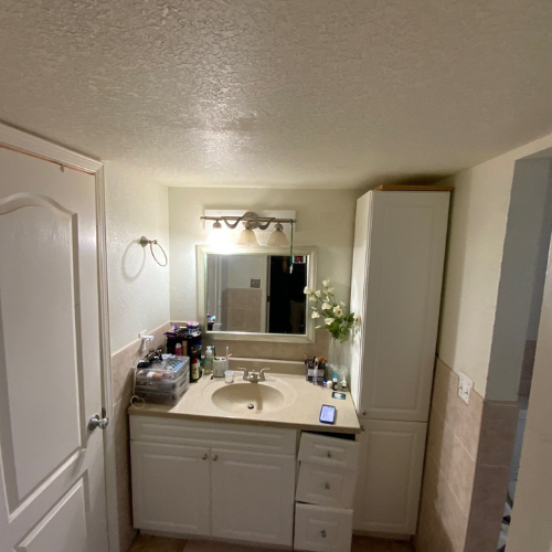 Bathroom with sink, vanity, mirror, storage cabinet, and open doorway.
