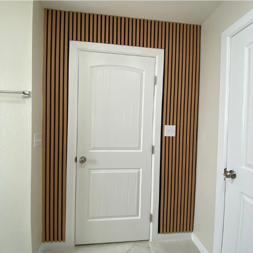 Bathroom with white door and vertical wood panel accent wall.