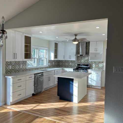 White kitchen with blue island and patterned backsplash. Hardwood floors.