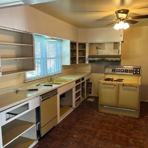 Kitchen with yellow appliances and cabinets. Brown floor and tan walls.