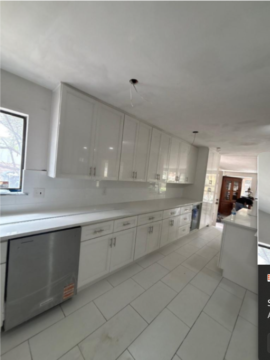 Bright modern kitchen with white cabinets, long countertop, and tiled floor in a spacious open room