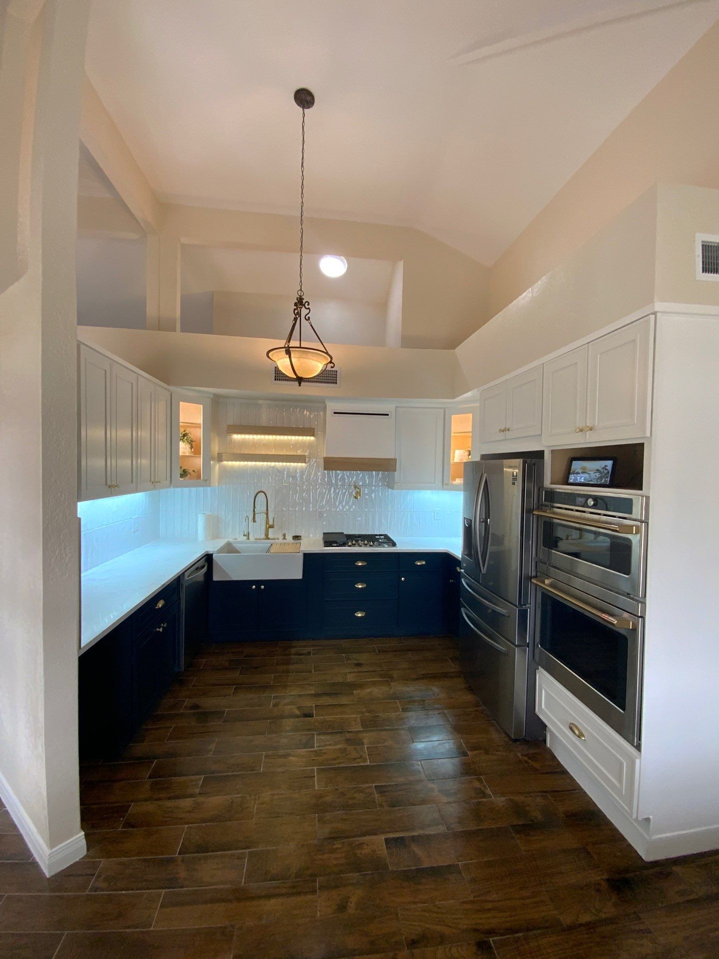 Modern kitchen with dark blue cabinets, white countertops, and stainless steel appliances.