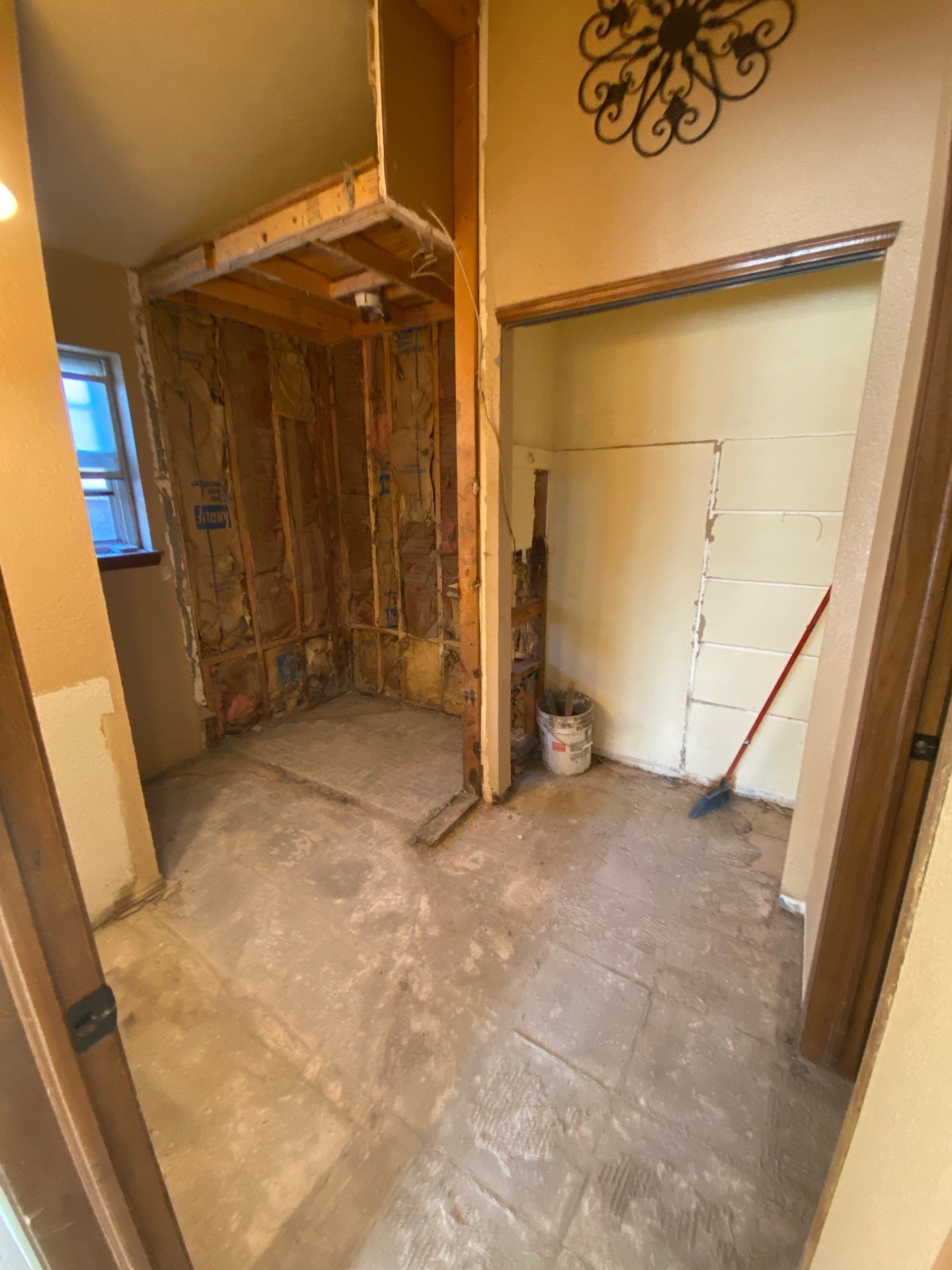 Bathroom remodel, walls stripped to studs. Shower stall on left, closet on right, concrete floor.