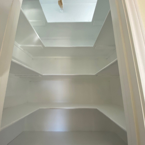 Empty white pantry with multiple shelves and a skylight.