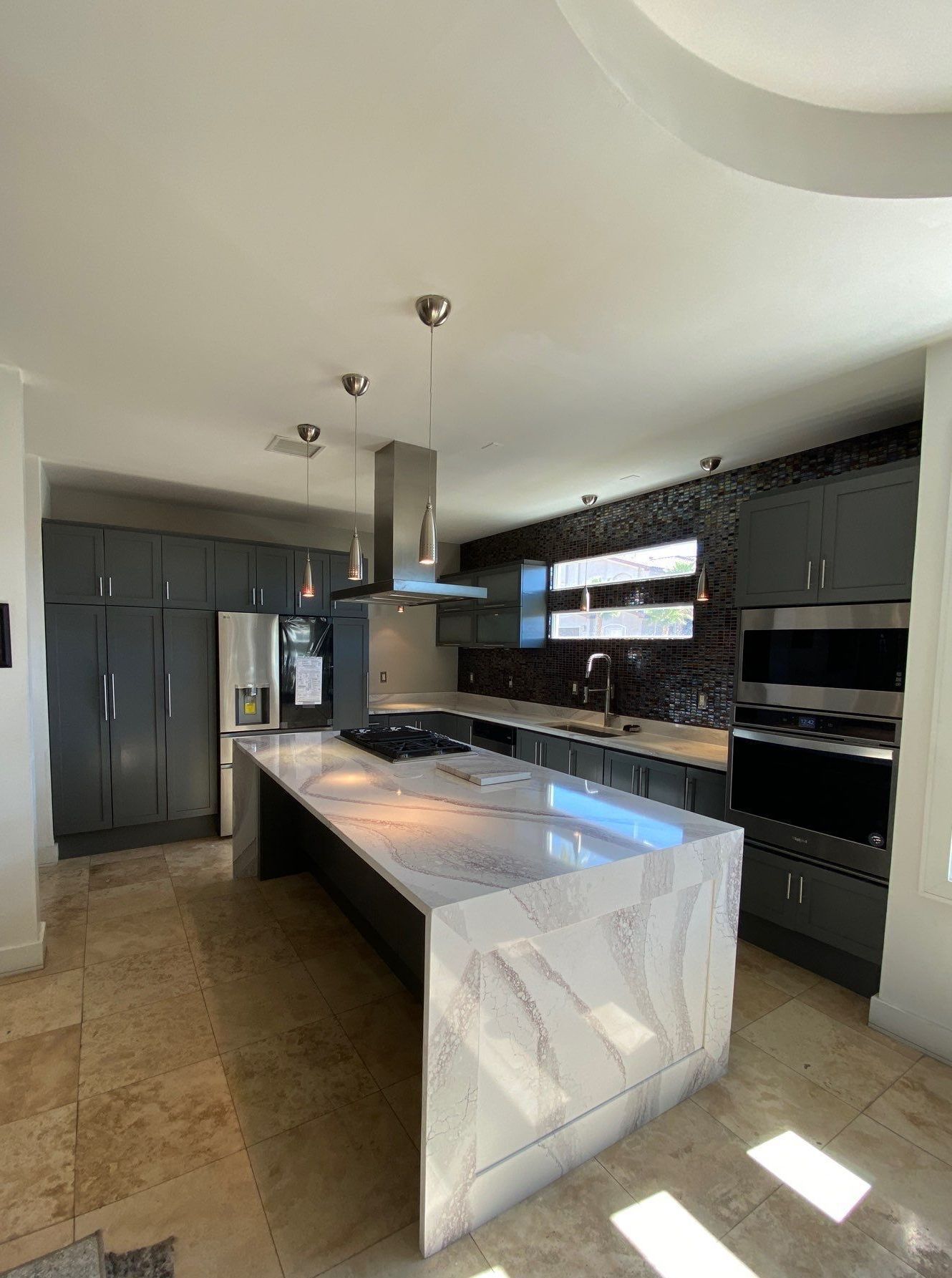 Modern kitchen with a gray island, cabinets, and a gas range.