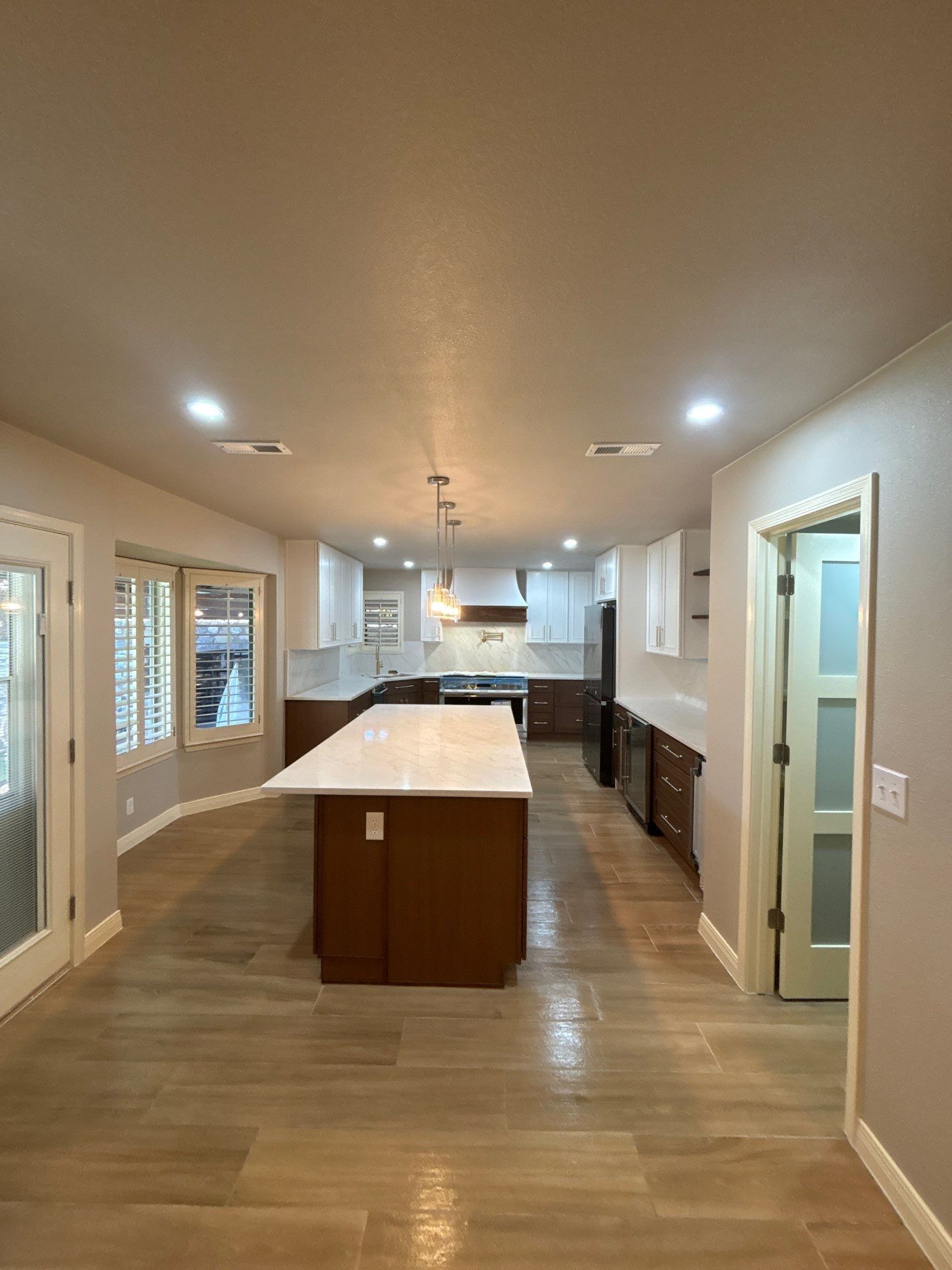Modern open kitchen with island, wood floors, recessed lights, and adjacent dining/living area