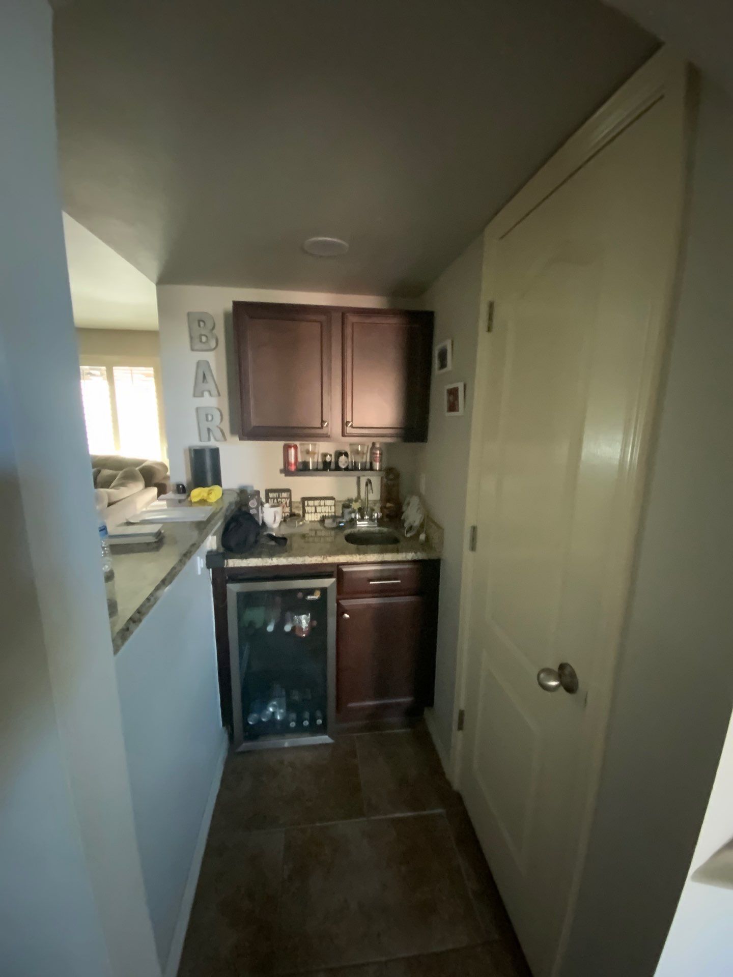 Narrow kitchen with dark cabinets, countertop, dishwasher, and a window on the left.