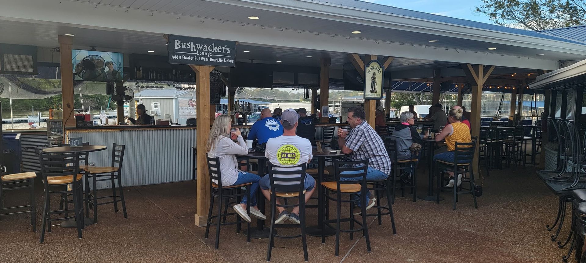 A group of people are sitting at tables outside of a restaurant.