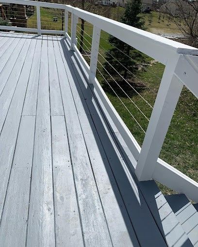 A wooden deck with a white railing and shadows on it