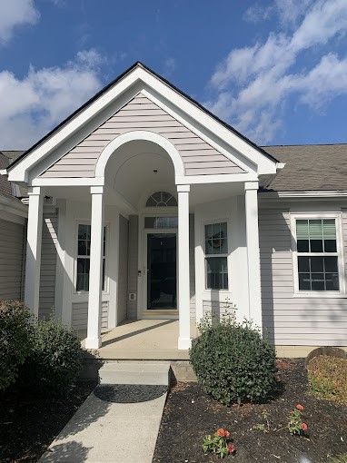 The front of a house with a porch and a walkway leading to it.