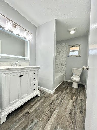 A bathroom with a toilet , sink and mirror.