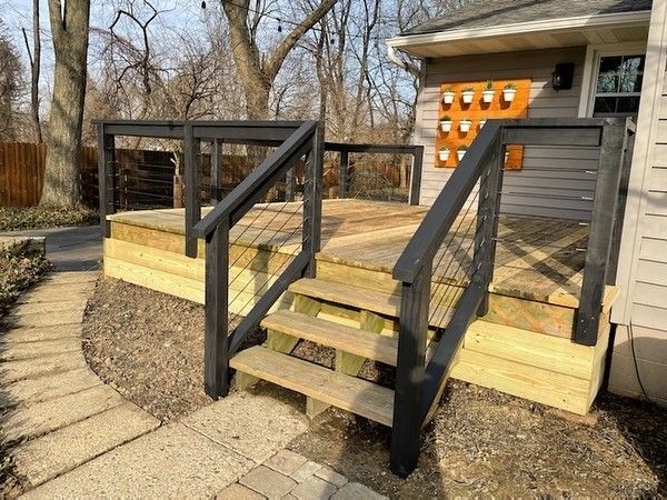 A wooden deck with stairs leading up to it in front of a house.