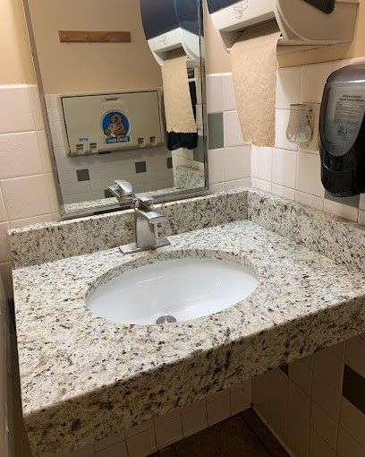 A bathroom sink with a granite counter top and a mirror.