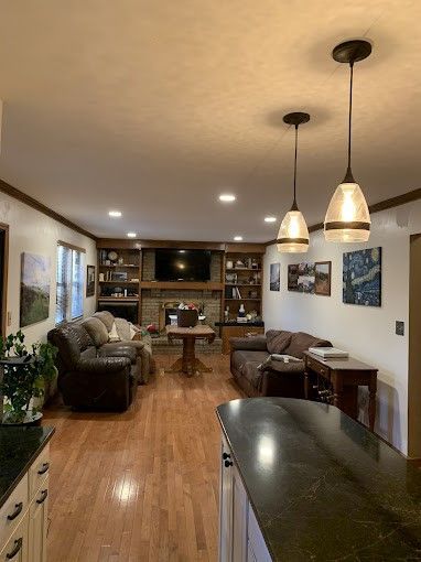 A living room with hardwood floors , a couch , a table , and a fireplace.