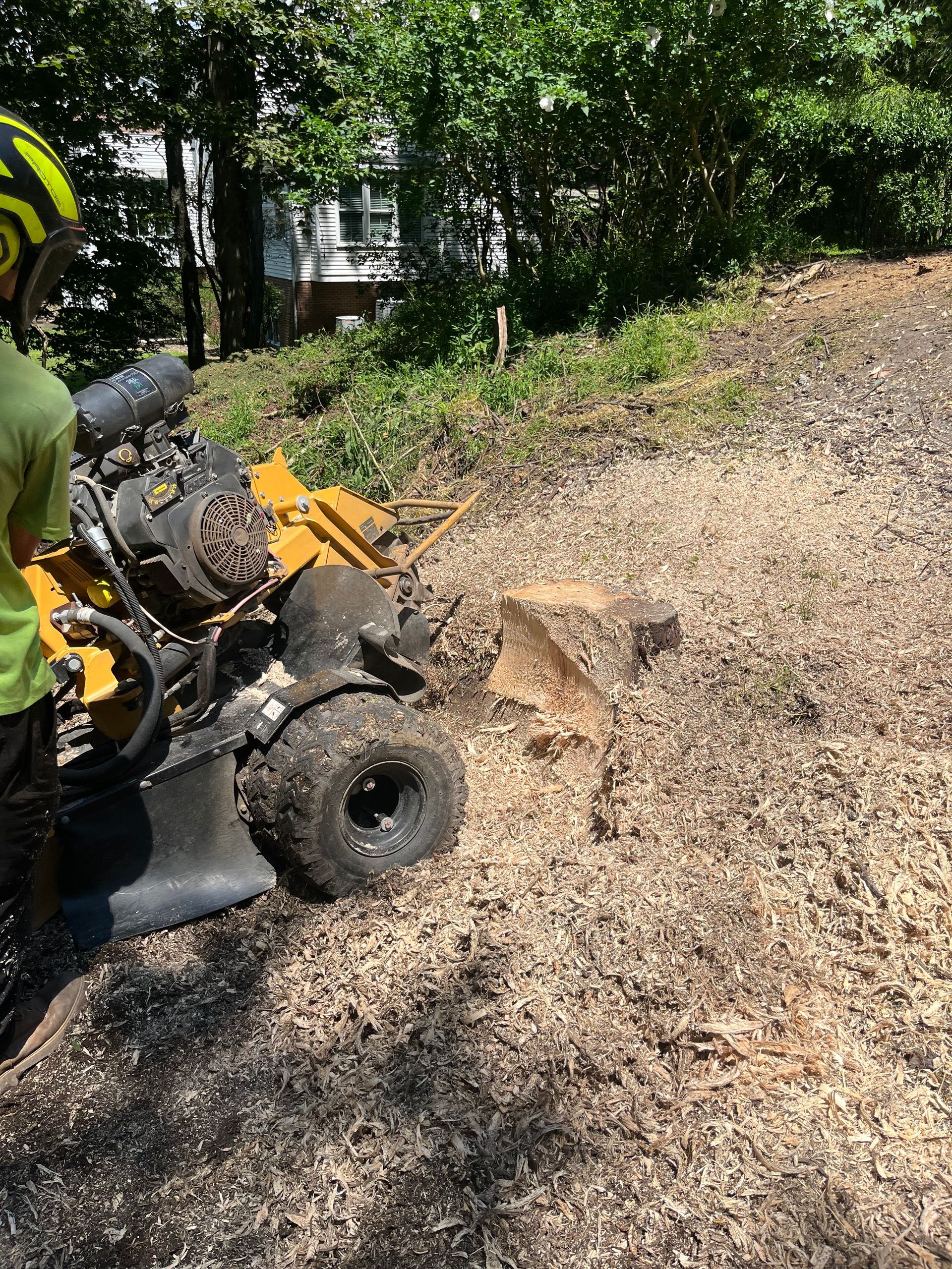 Person on an ATV beside a dirt mound on a wooded trail, with a scoop of soil in front.