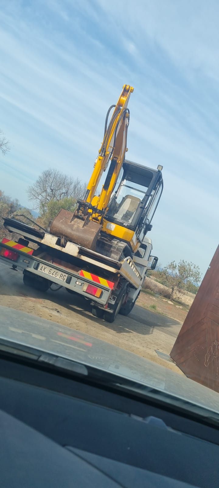 Un escavatore giallo è parcheggiato sul retro di un carro attrezzi.
