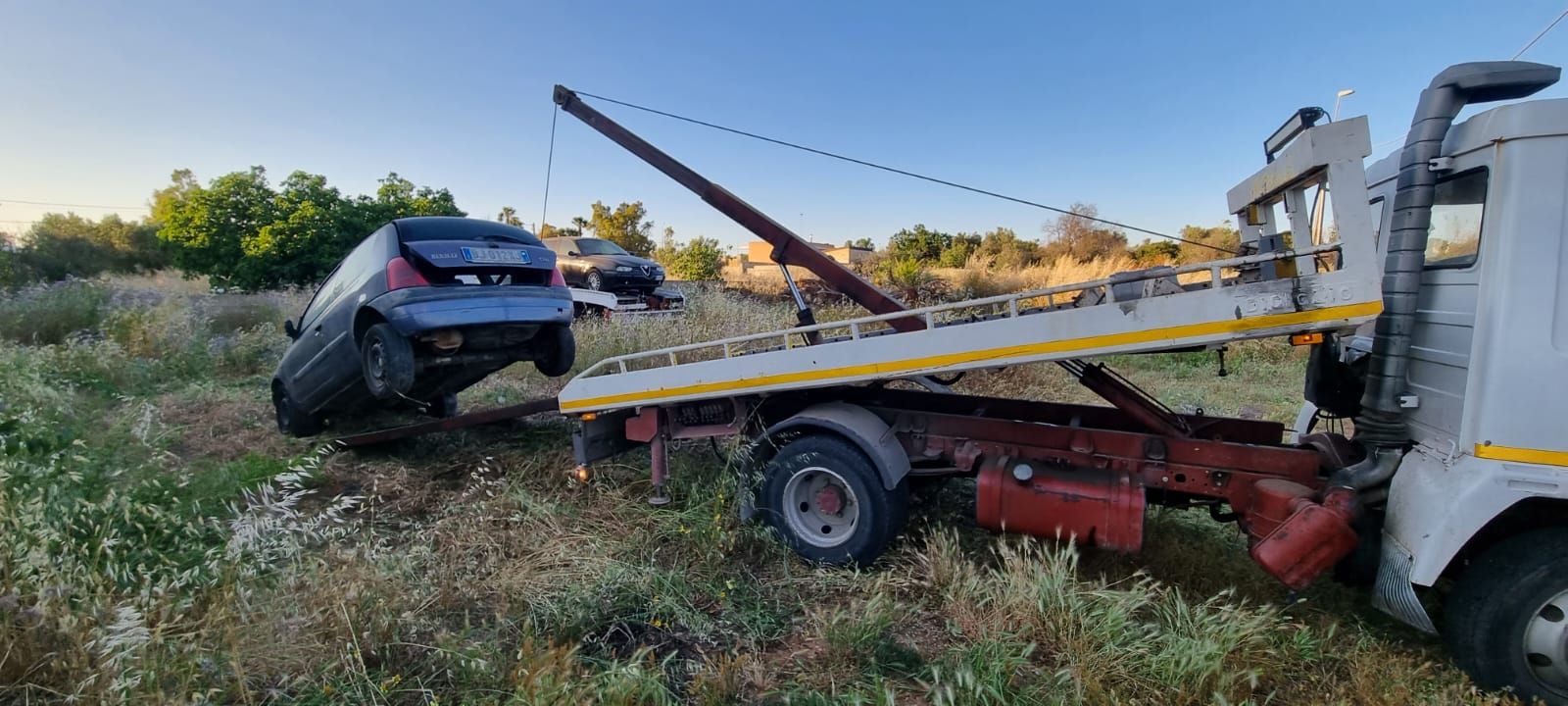 Un'auto viene trainata da un carro attrezzi in un campo.