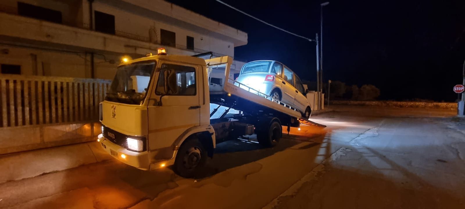 Un carro attrezzi sta trainando un'auto lungo una strada di notte.