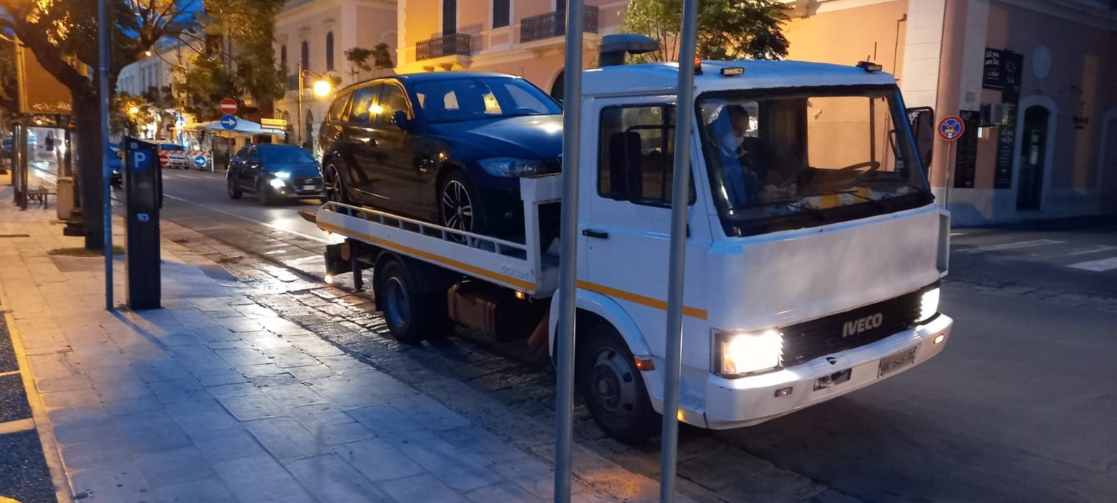 Un carro attrezzi con un'auto sul retro è parcheggiato sul ciglio della strada.