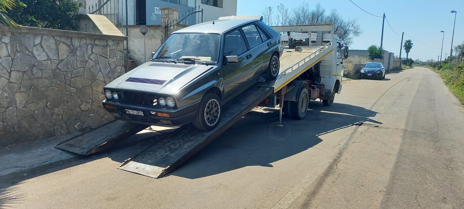 Un'auto viene trainata lungo una strada da un carro attrezzi.