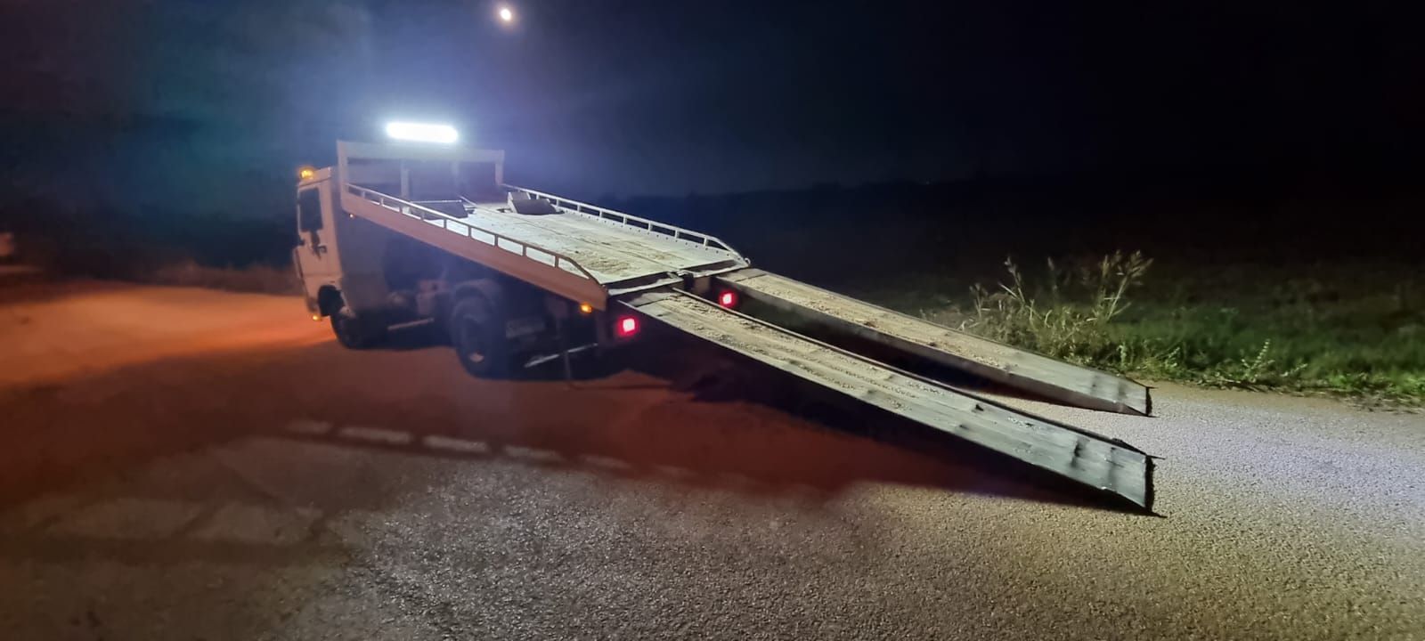 Un carro attrezzi è parcheggiato sul ciglio della strada di notte.