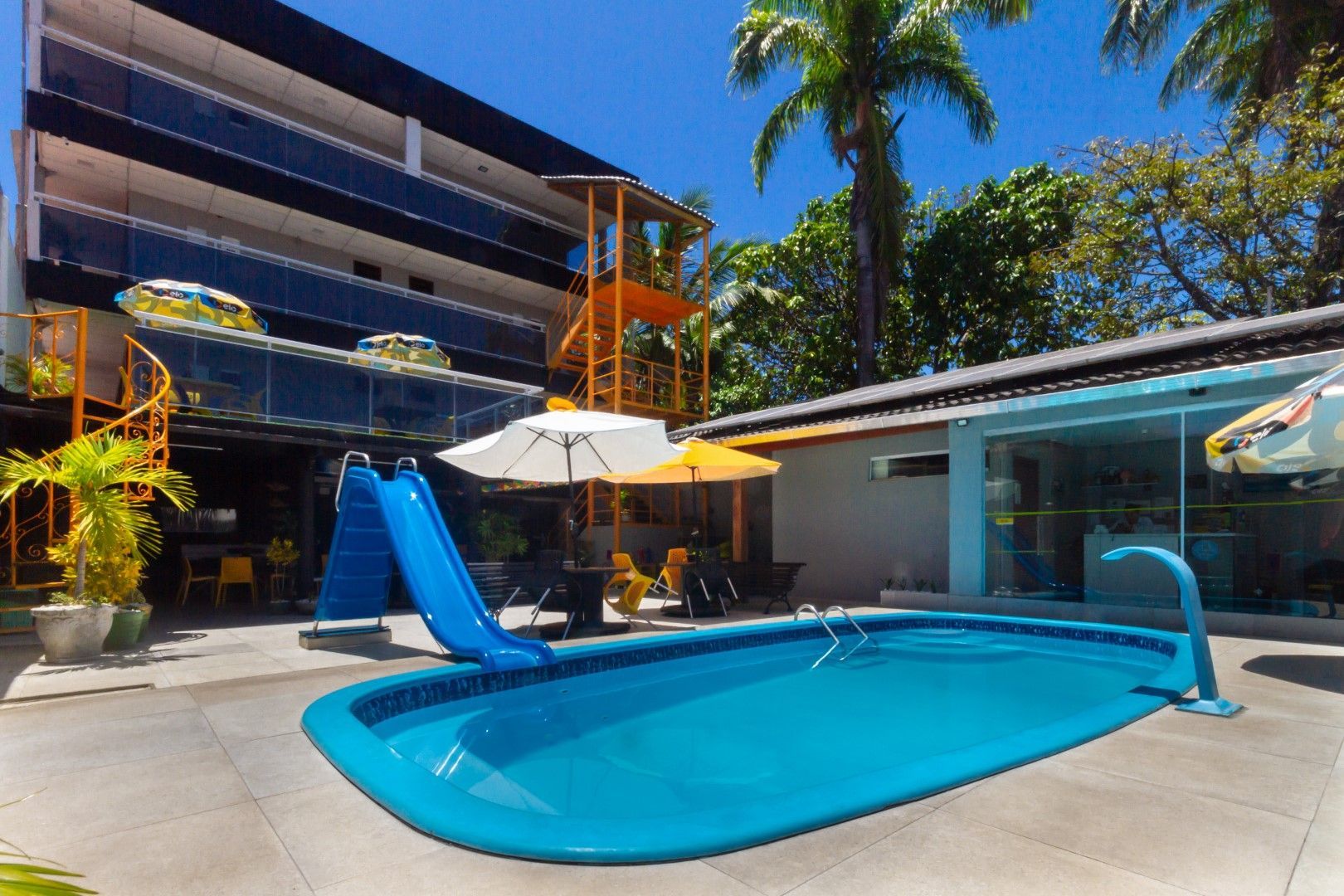 Uma piscina com escorregador e guarda-sóis em frente a um prédio