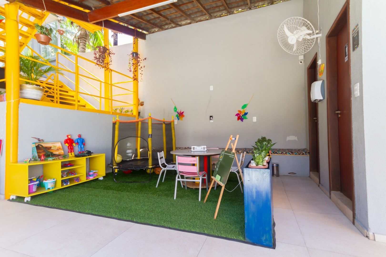 Uma sala com uma mesa, cadeiras e um trampolim.
