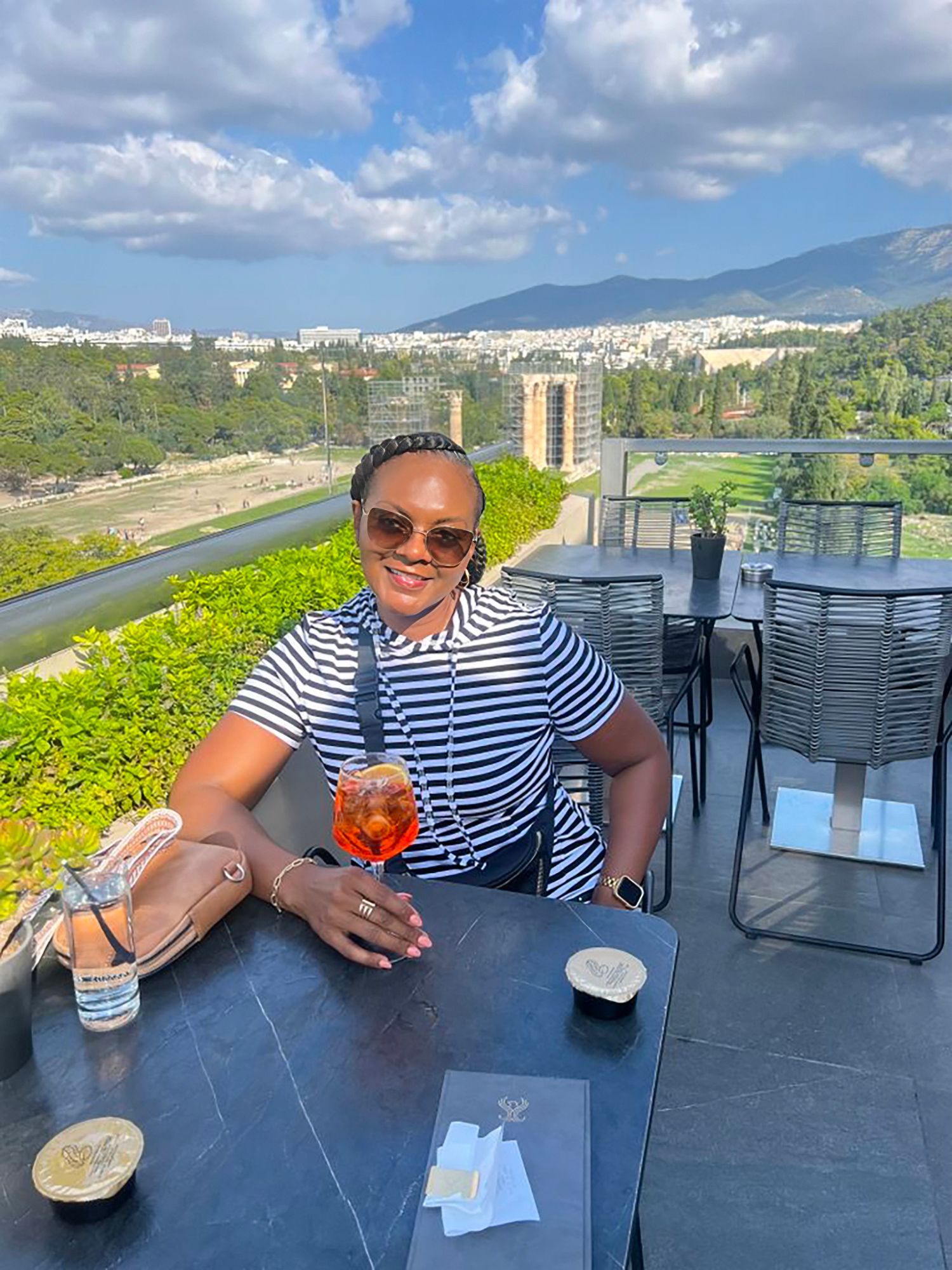 Black woman enjoying a drink on the rooftop in Athens, Greece
