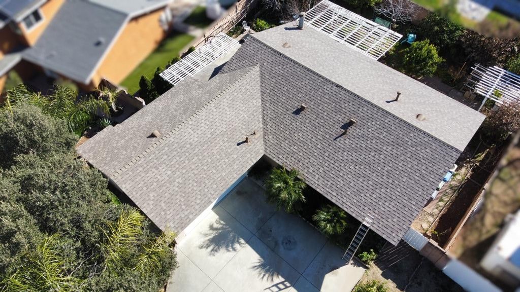 Overhead view of a house with a gray shingled roof and a concrete driveway.