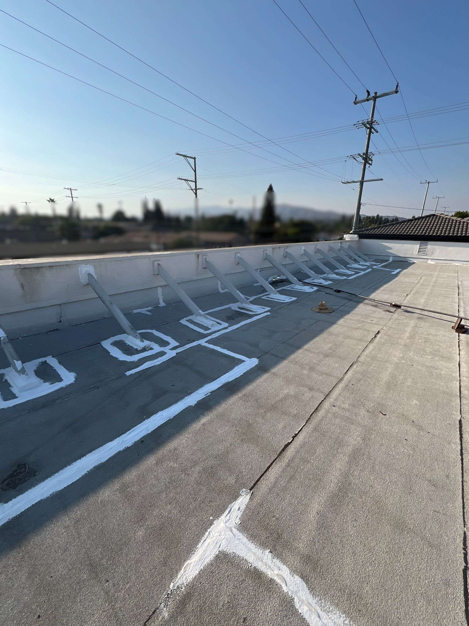 Concrete water channel with white markings, power lines, and a clear blue sky.