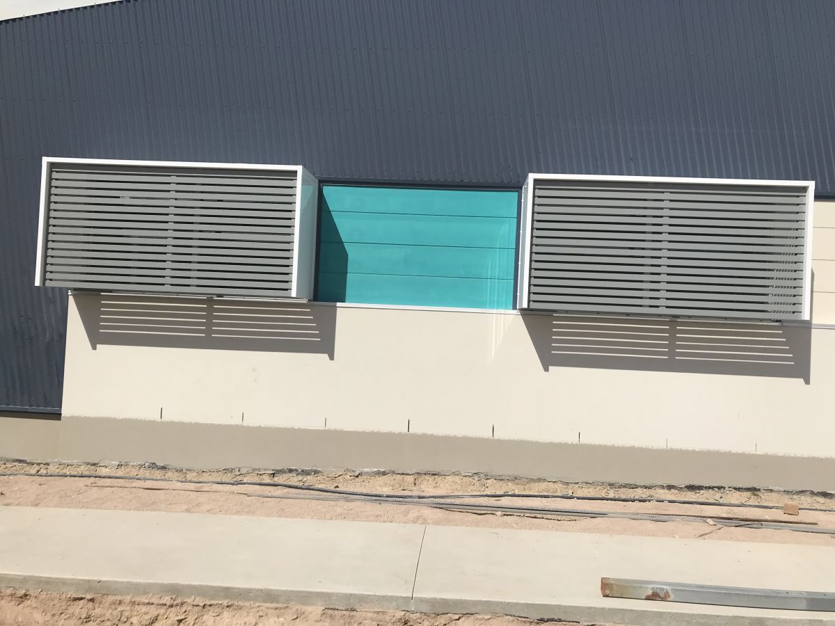 Two Gray, Slatted Air Conditioning Units With Silver Frames On A Light Beige Wall — Custom Steel Fab in Garbutt, QLD