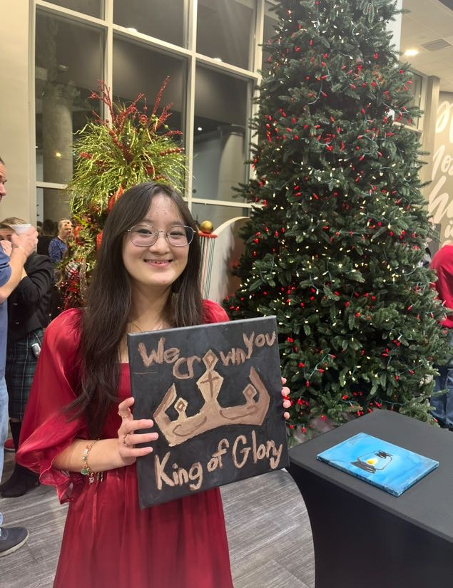 Woman in red dress holding a painting that says 