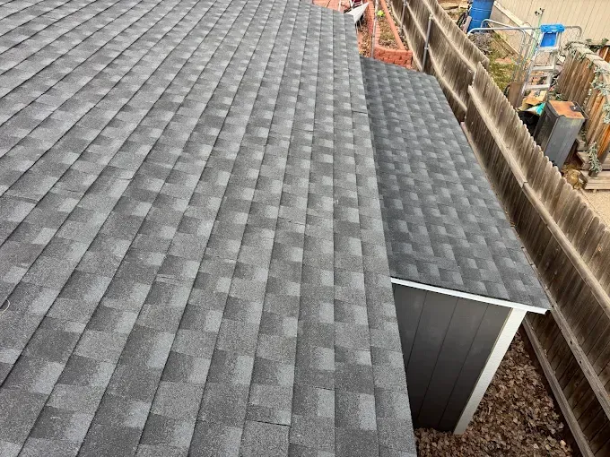 Gray shingled roof with a small metal dormer beside an open construction area
