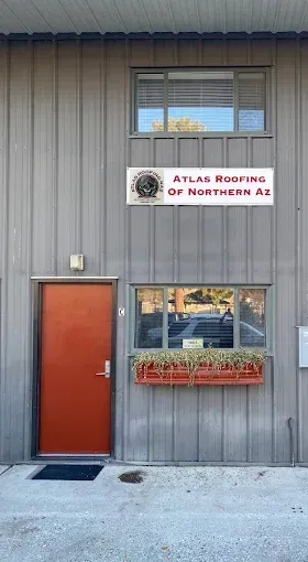 Gray building with orange door, window flower box, and sign reading “Atlas Roofing of Northern AZ”