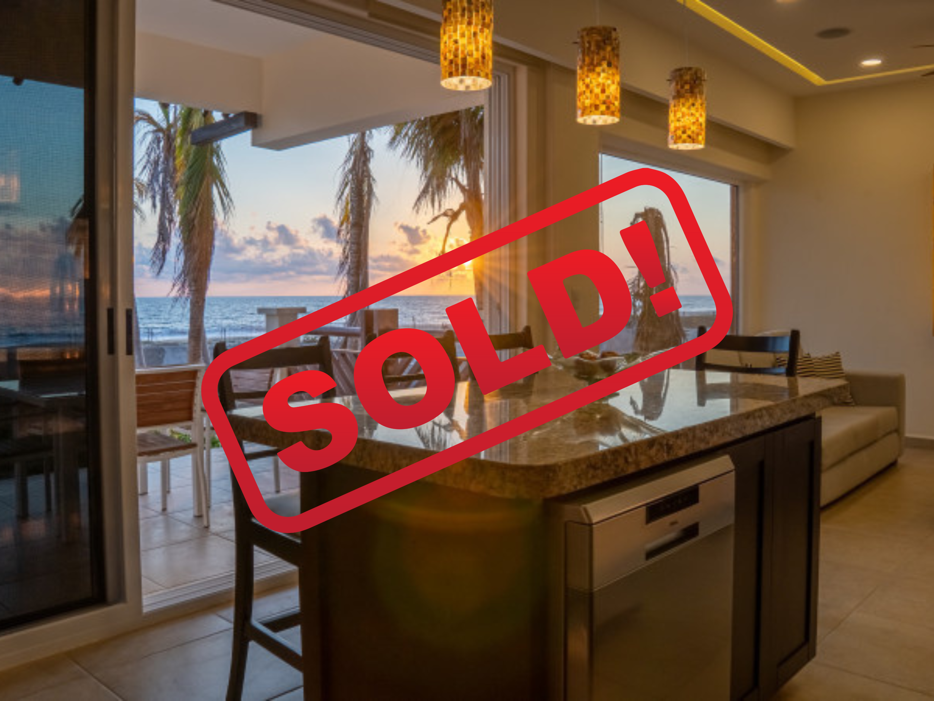 Interior view of a kitchen with an island, beachfront view, SOLD stamp overlaid.