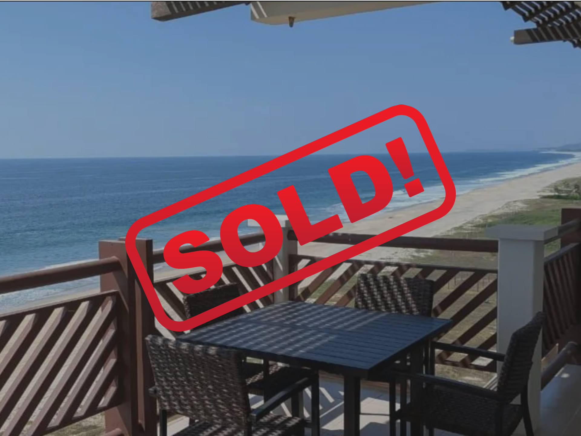 Balcony table overlooking the ocean with red “SOLD!” stamp overlay
