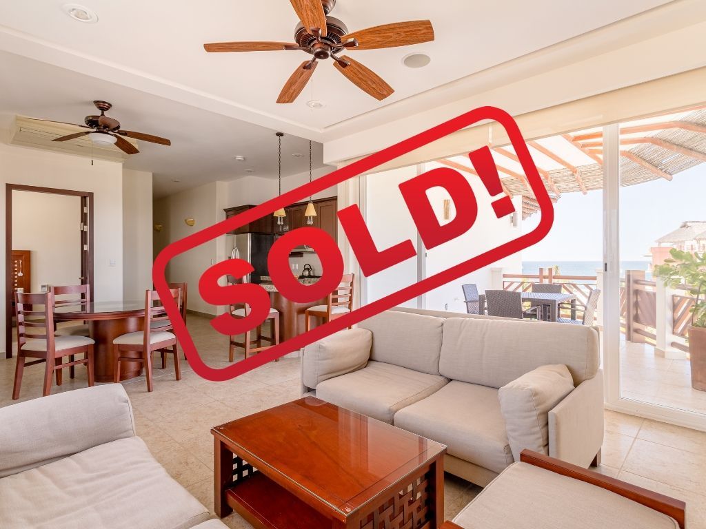 Sold sign over a bright living room with beige sofa, coffee table, and ceiling fans