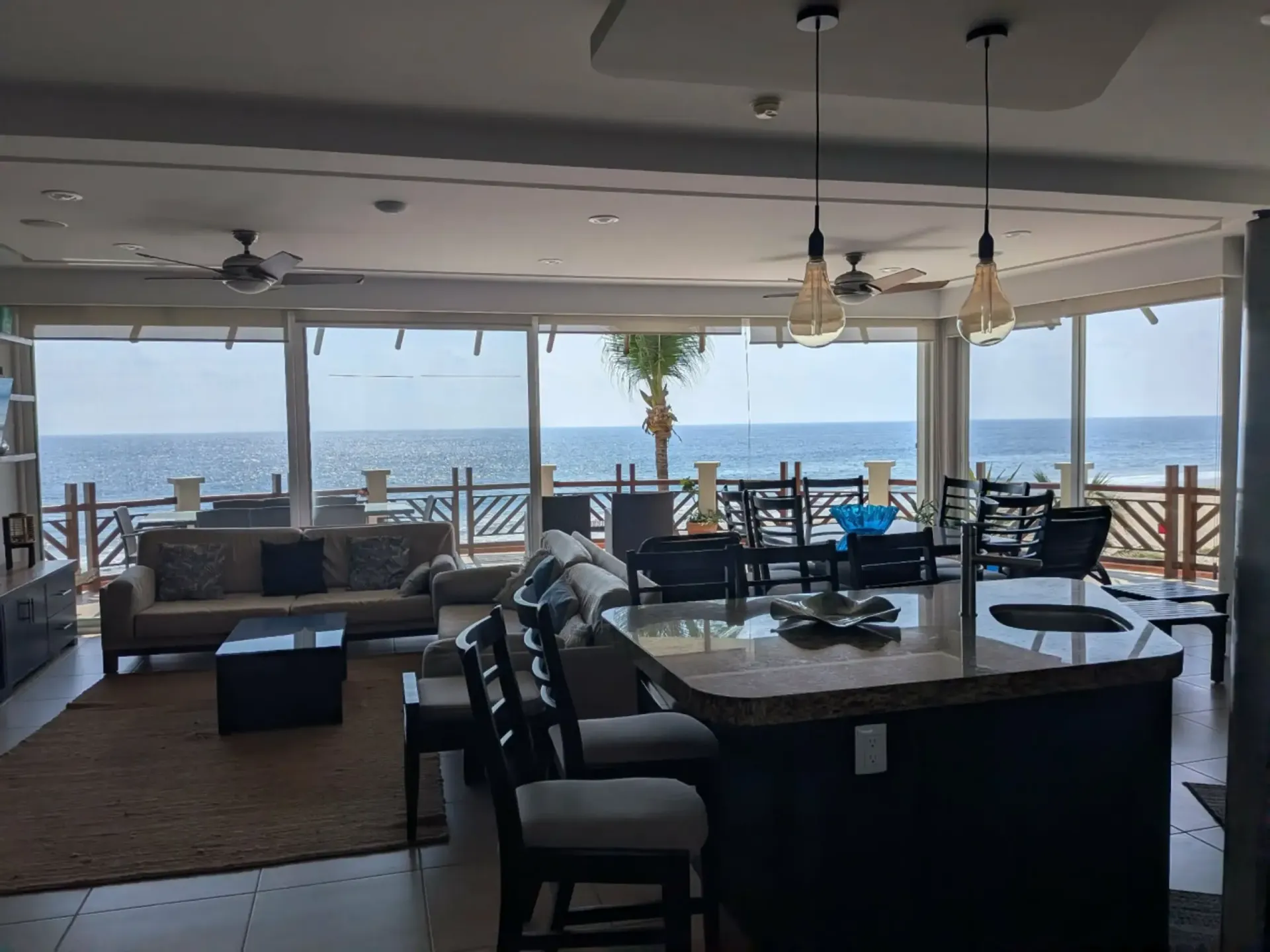 Seaside restaurant patio with tables and chairs overlooking the ocean through large open windows