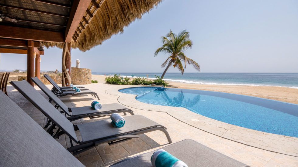 Lounge chairs by a pool overlooking the ocean at Vivo Resort.