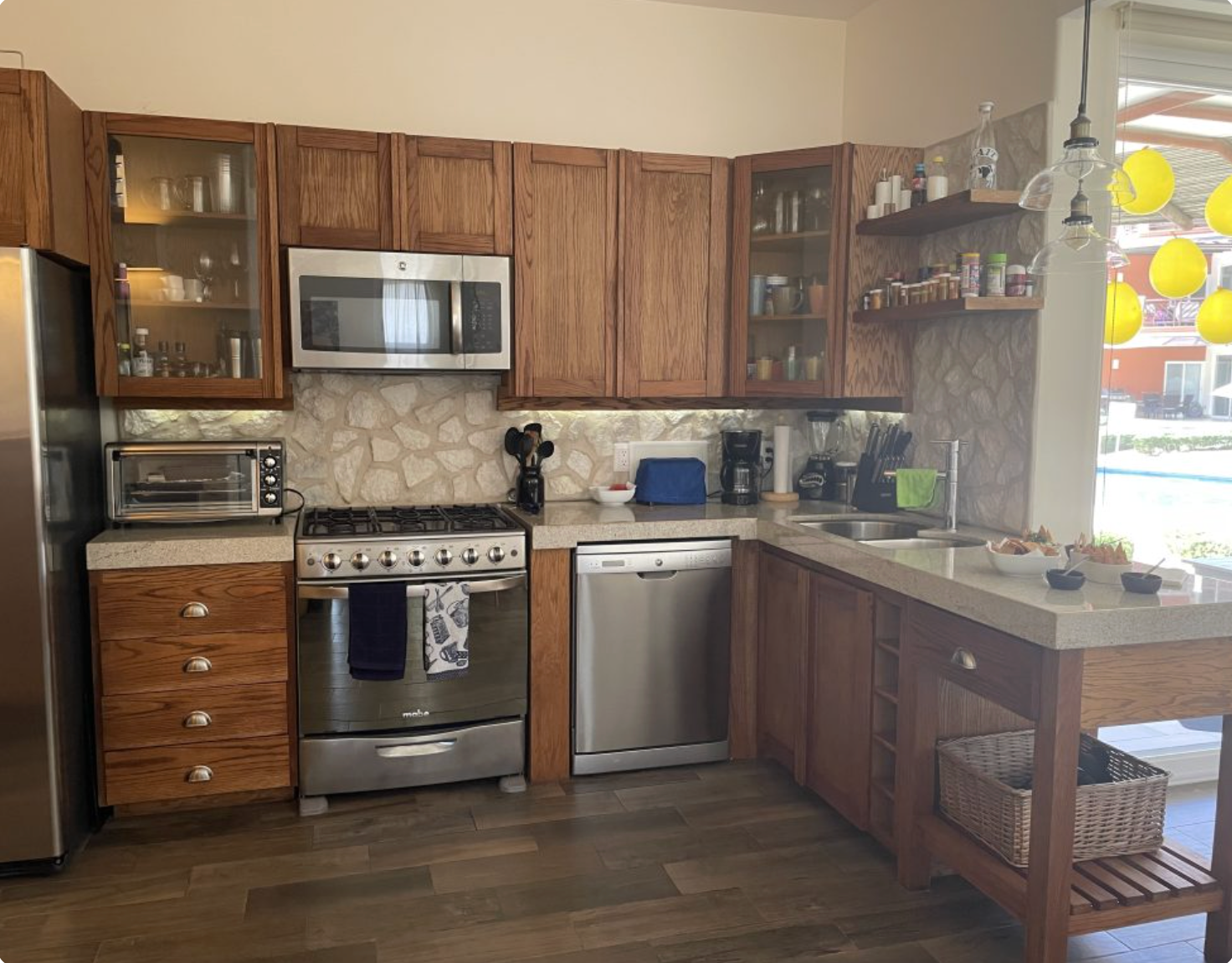 Wooden kitchen with stainless steel appliances and light countertops.